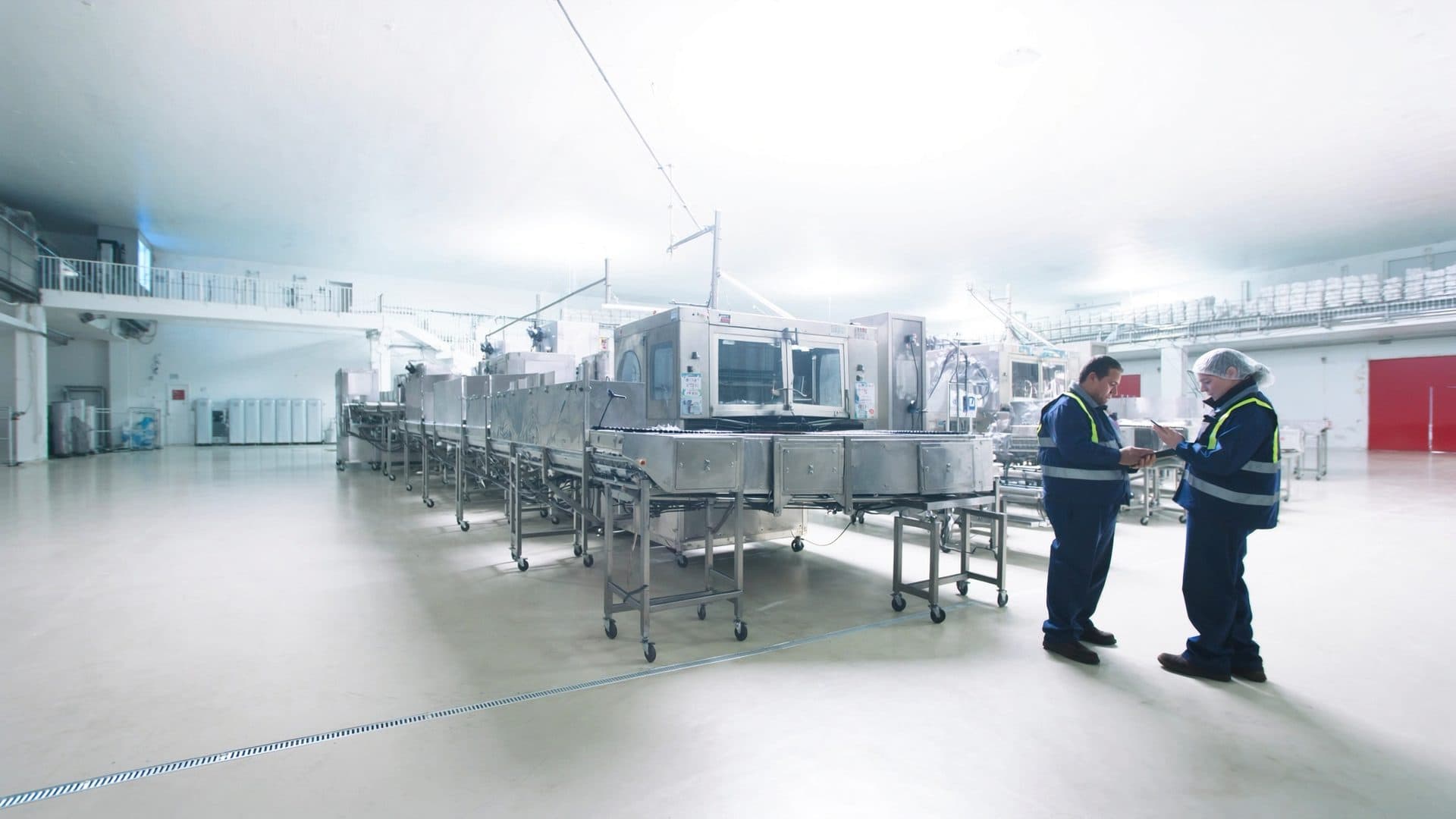 Two workers reviewing production notes together on a spotless food manufacturing floor